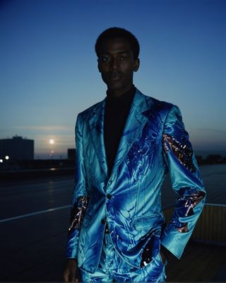 a man in a blue suit standing in front of a building