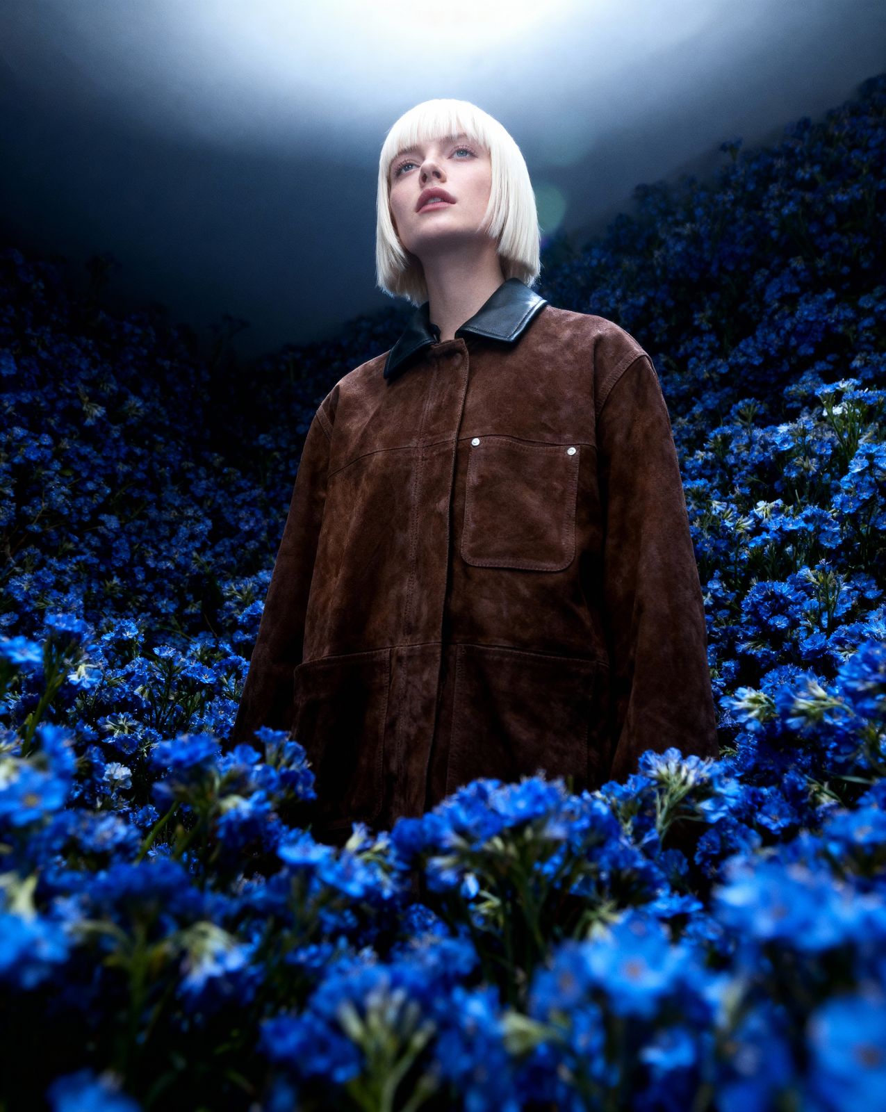 a woman standing in a field of blue flowers