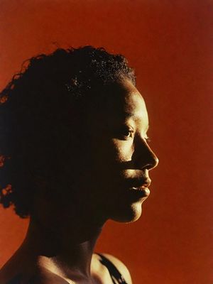 a man with curly hair standing in front of a red wall