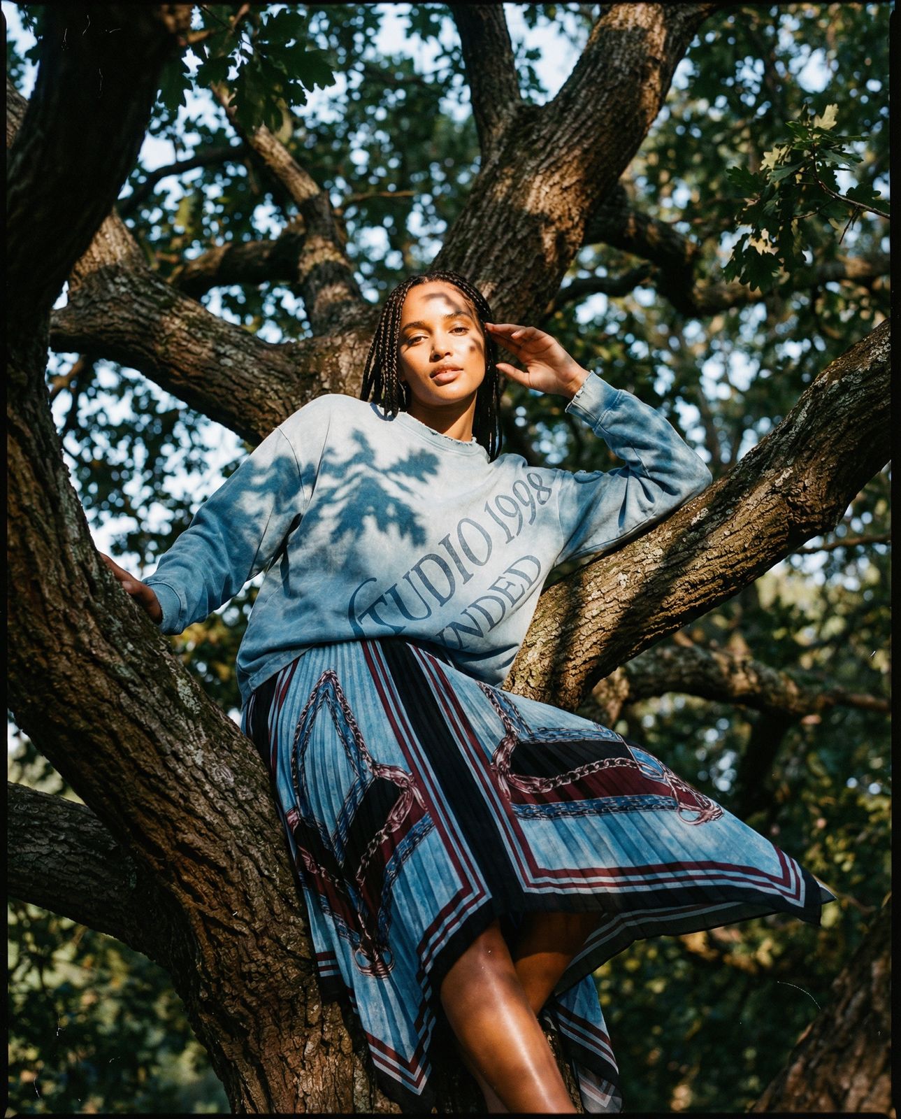 a woman sitting in a tree with her hands on her head