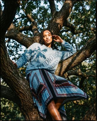 a woman sitting in a tree with her hands on her head