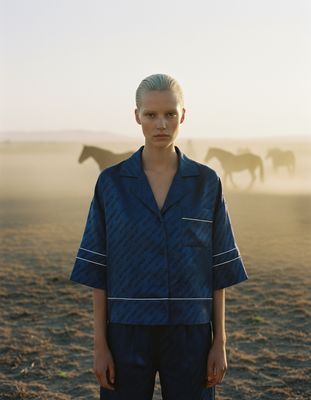 a man standing in a field with horses in the background