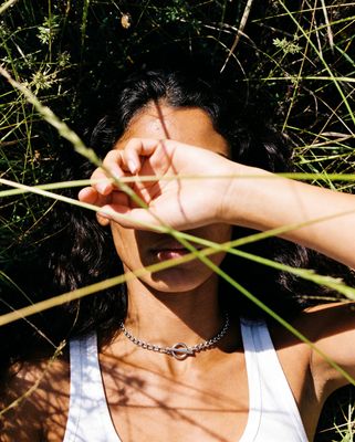a woman in a tank top laying in the grass