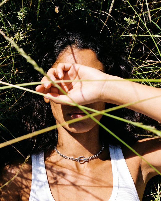 a woman in a tank top laying in the grass