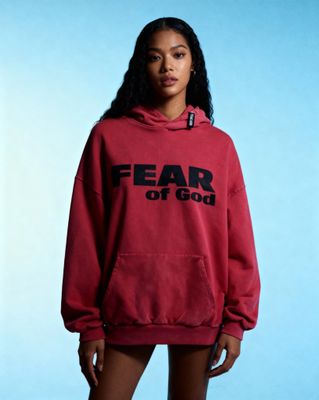 a woman wearing a red hoodie that says fear of god
