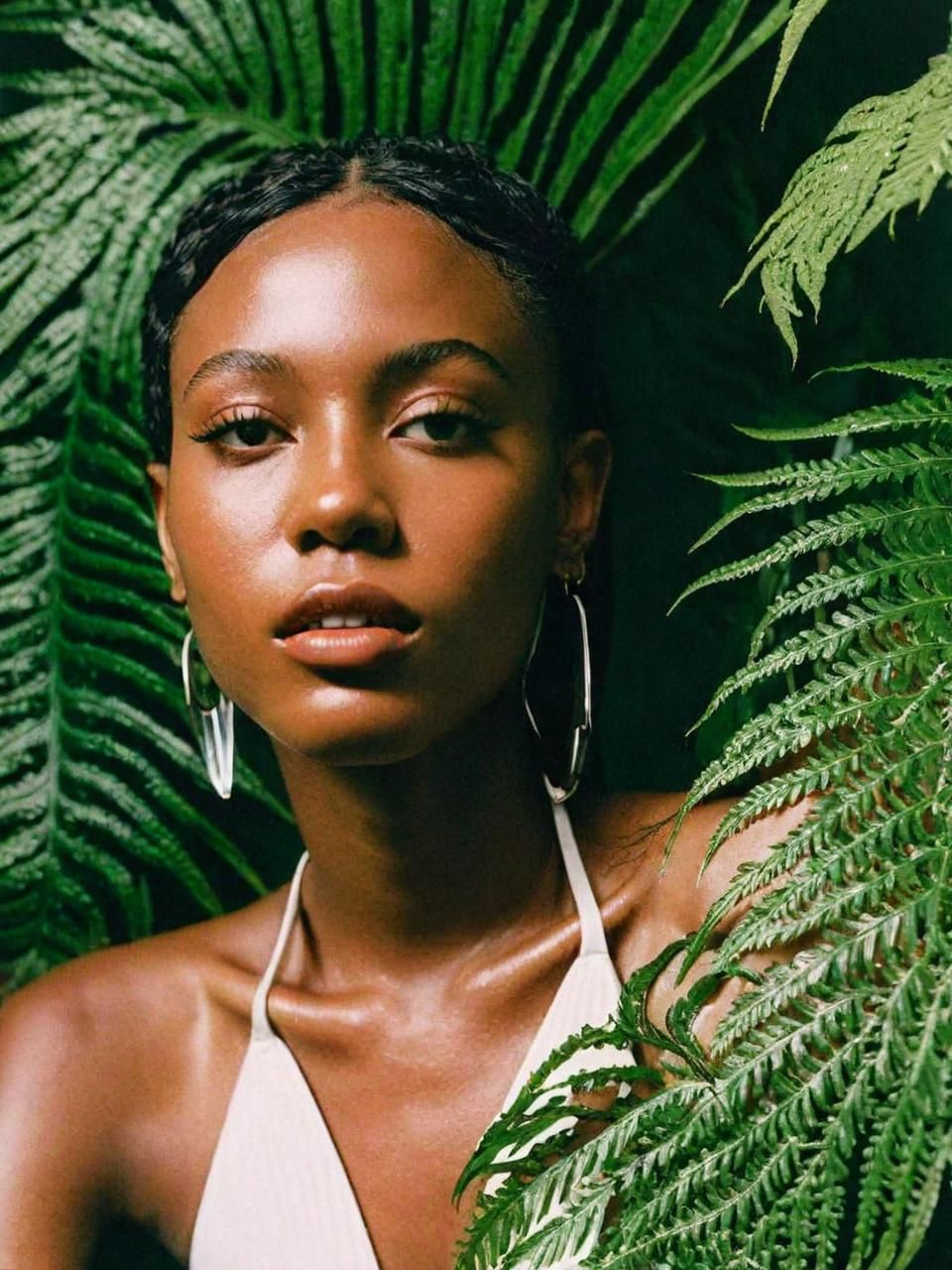 a woman standing in front of a green plant