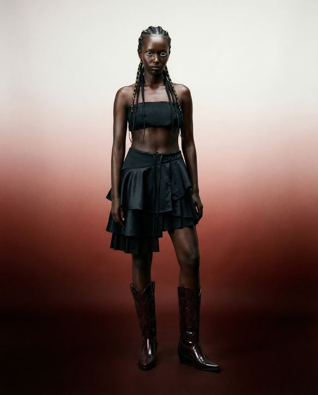 a woman in a skirt and boots posing for a picture