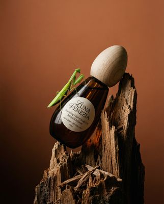 a bottle of liquid with a green insect on top of it