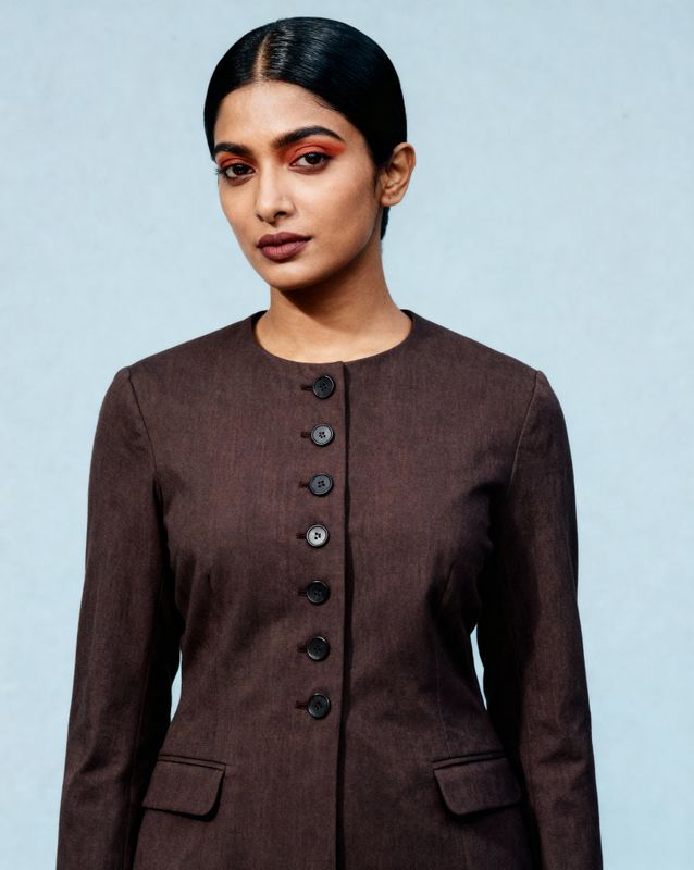 a woman wearing a brown jacket and black pants