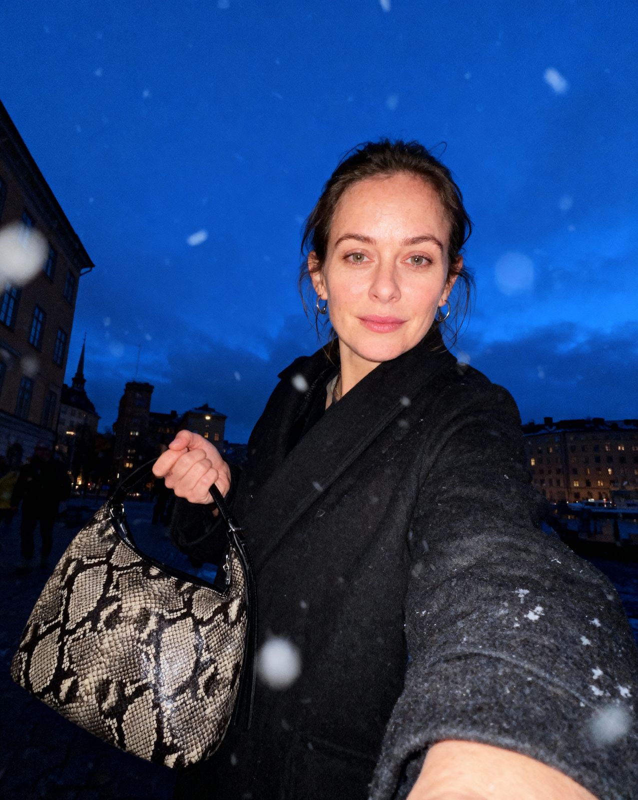 a woman holding onto a snake skin purse