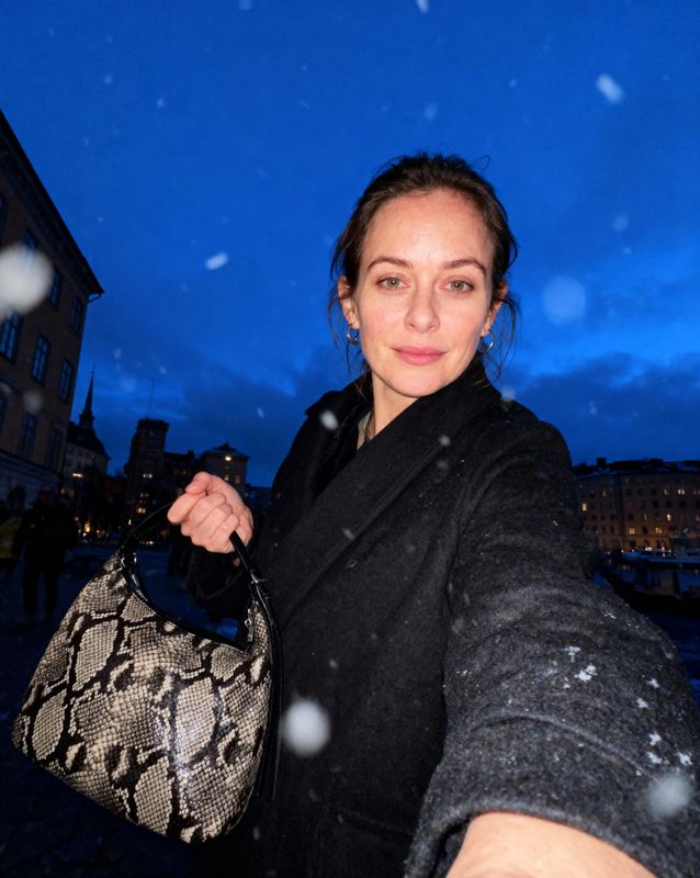 a woman holding onto a snake skin purse