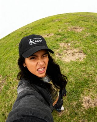 a woman taking a selfie in front of a grassy hill