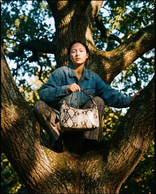 a woman sitting in a tree holding a purse