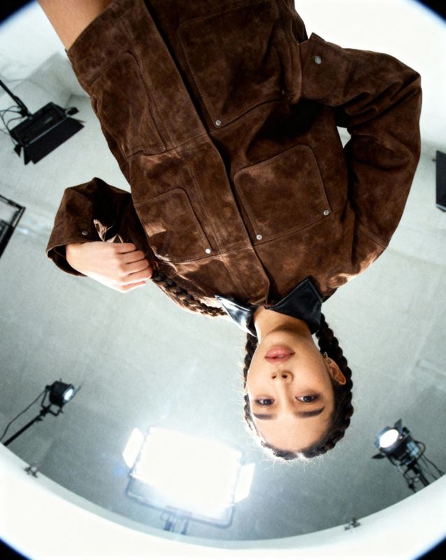 a person standing in front of a mirror wearing a brown jacket