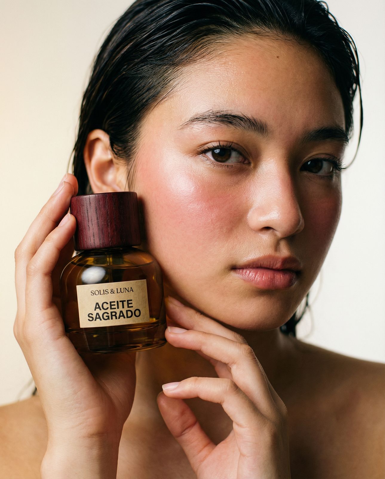 a woman holding a bottle of perfume in front of her face