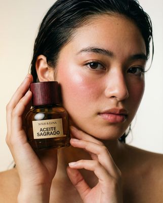 a woman holding a bottle of perfume in front of her face
