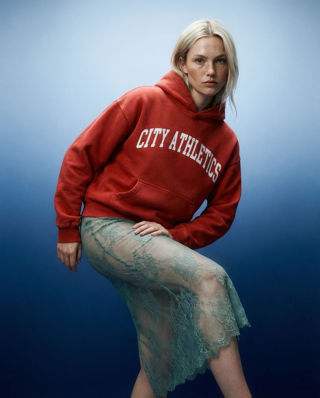 a woman in a red sweatshirt and skirt