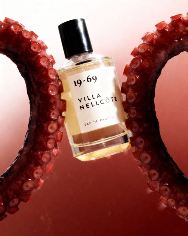 a bottle of perfume sitting on top of a pair of scissors