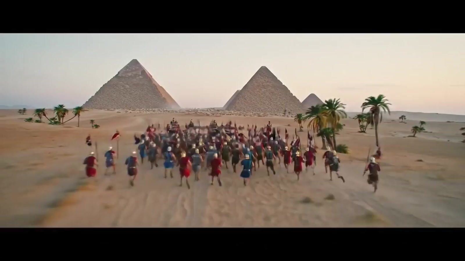 a group of people walking across a sandy field