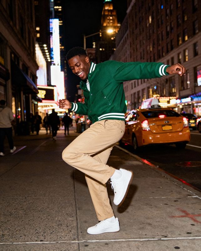 a man in a green jacket doing a trick on a skateboard