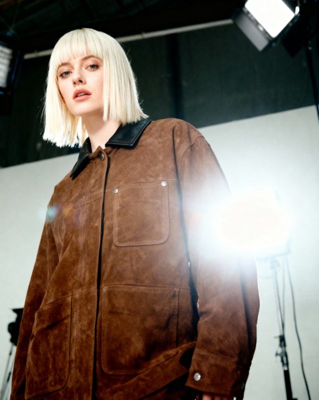 a woman with blonde hair wearing a brown jacket