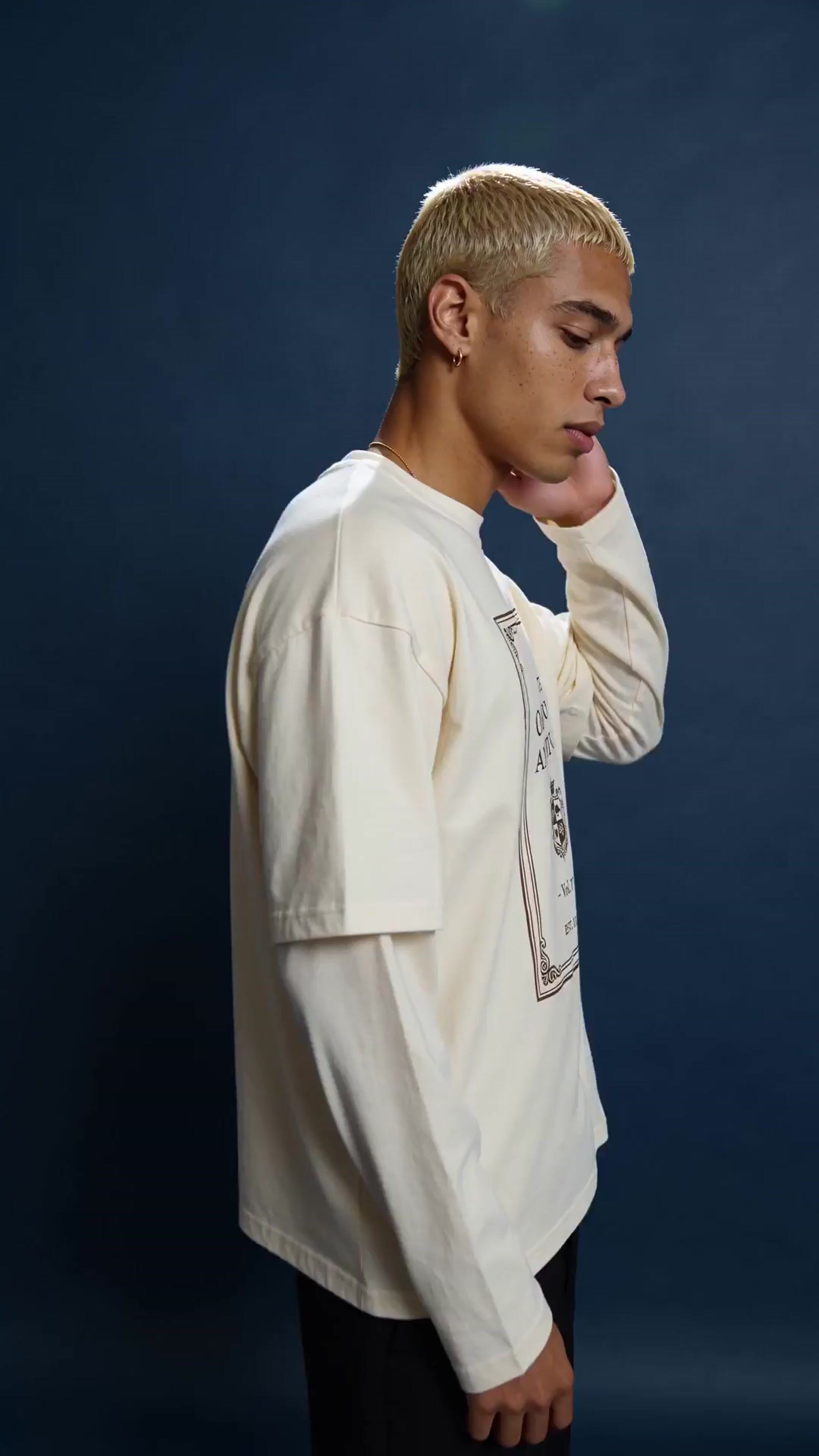 a man in a white shirt is holding his hand to his face