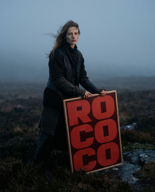 a woman holding a sign that says rocco
