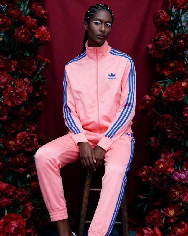 a woman sitting on a stool in a pink outfit