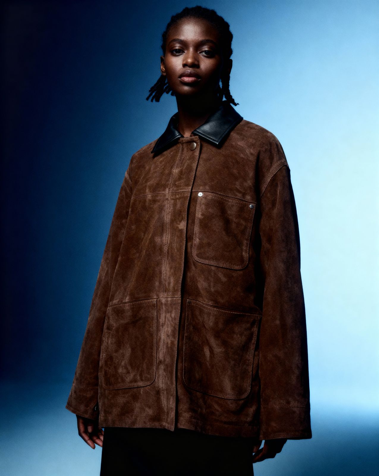a woman wearing a brown jacket and black pants