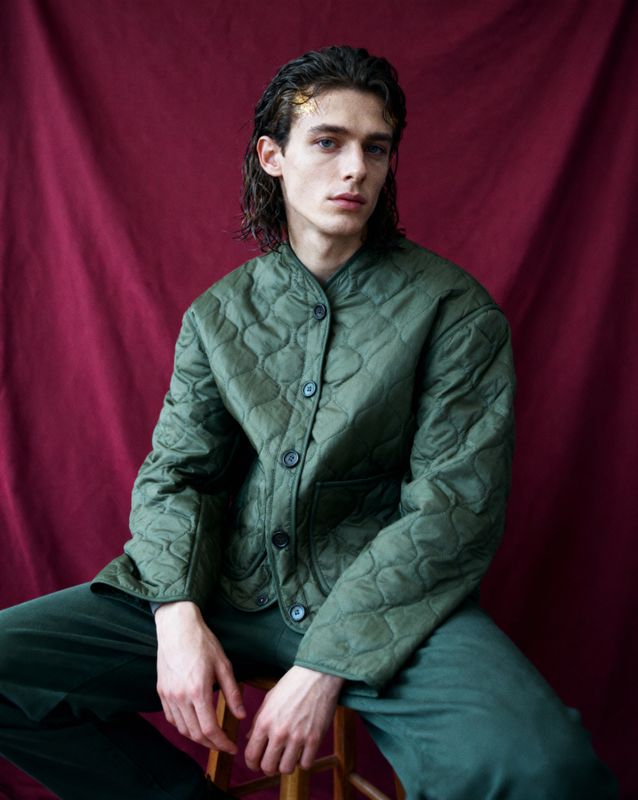 a man sitting on a chair wearing a green jacket