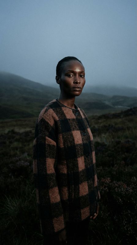 a woman standing in a field with a mountain in the background