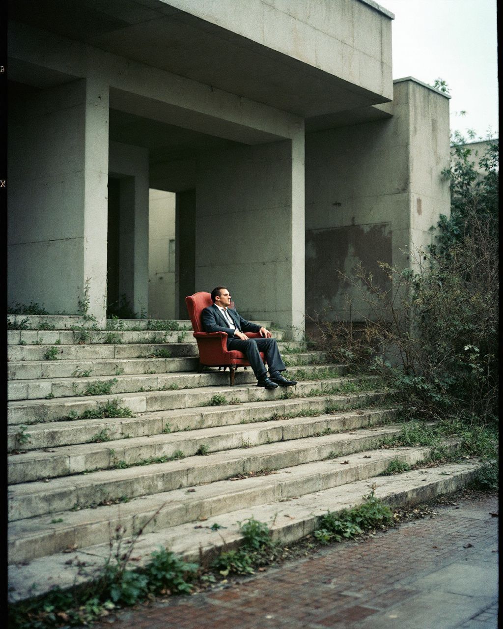 a man sitting on a red chair in front of a building