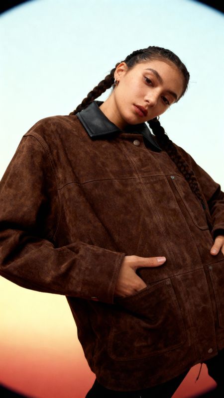 a woman in a brown jacket is posing for a picture