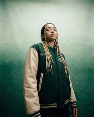 a woman with dreadlocks standing in front of a green wall