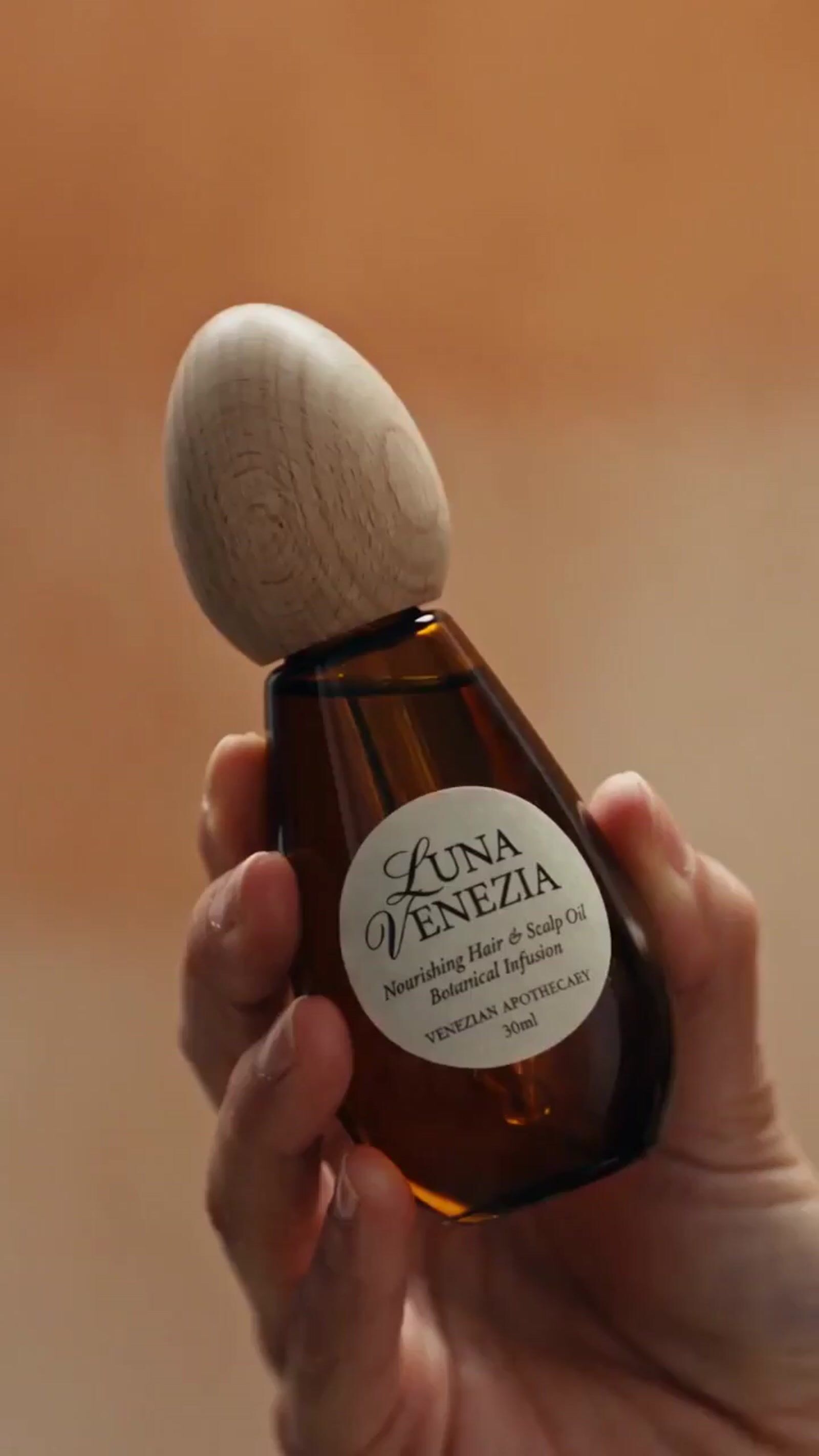 a hand holding a bottle of soap with a wooden stopper