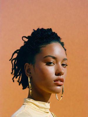 a woman with dreadlocks wearing a yellow shirt