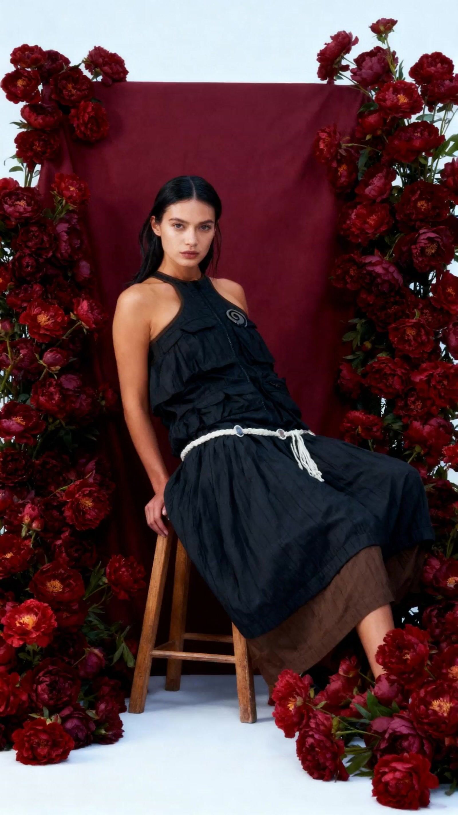 a woman sitting in a chair surrounded by flowers