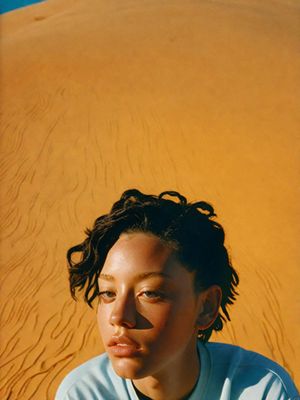 a woman sitting in front of a sand dune