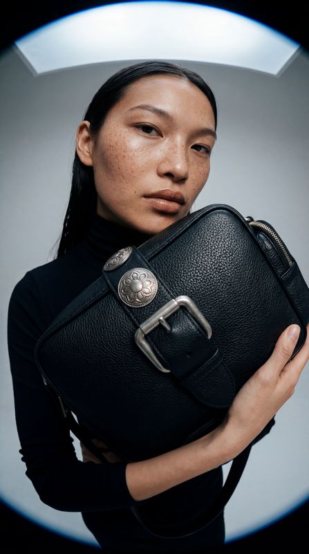 a woman holding a black purse in her hands