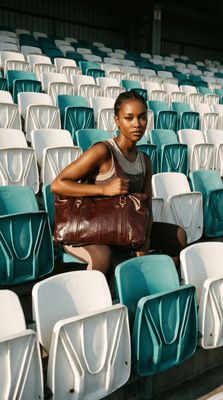 a woman sitting in a stadium holding a purse