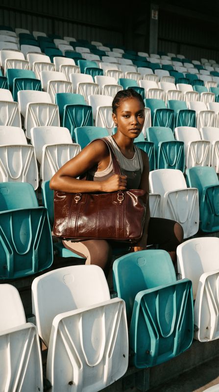 a woman sitting in a stadium holding a purse