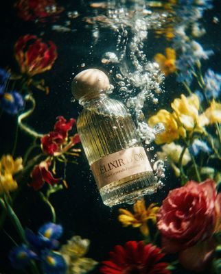 a close up of a bottle of perfume surrounded by flowers