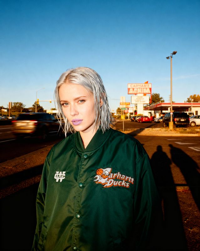 a woman with white hair standing in front of a gas station