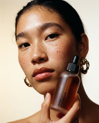 a woman with freckled hair holding a bottle of sunscreen