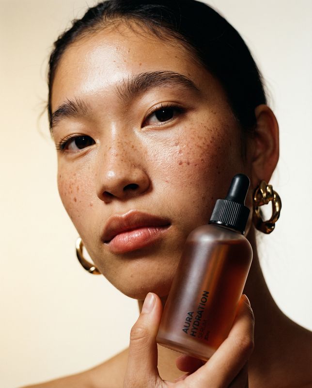 a woman with freckled hair holding a bottle of sunscreen