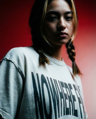 a woman with a braid standing in front of a red background