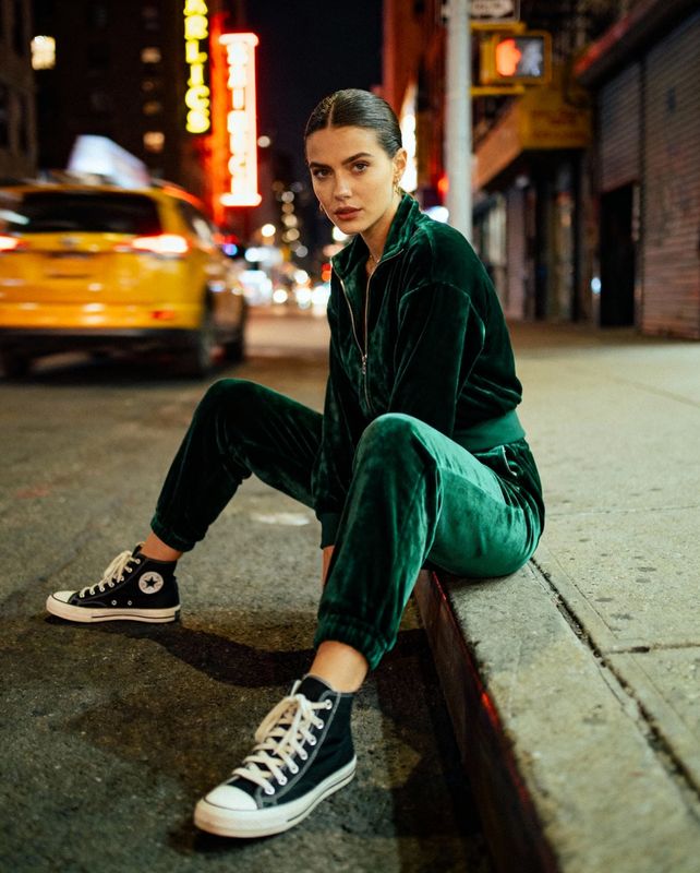 a woman sitting on a curb in a green outfit