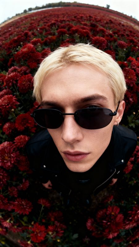 a man wearing sunglasses is standing in front of flowers
