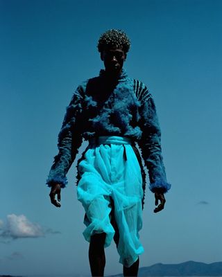 a man in a blue outfit walking on a beach