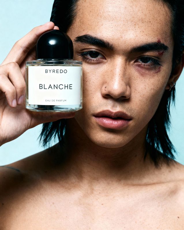 a woman holding a bottle of bleu de blancche